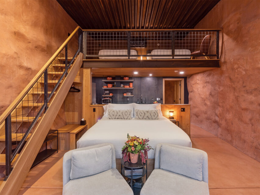 A bed, chairs, and staircase in a hotel room at Honey Rock Landing in Delta County