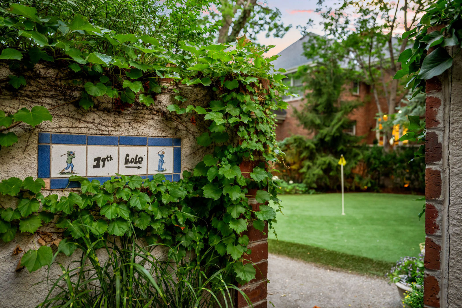 19th hole sign on a stone wall covered in ivy