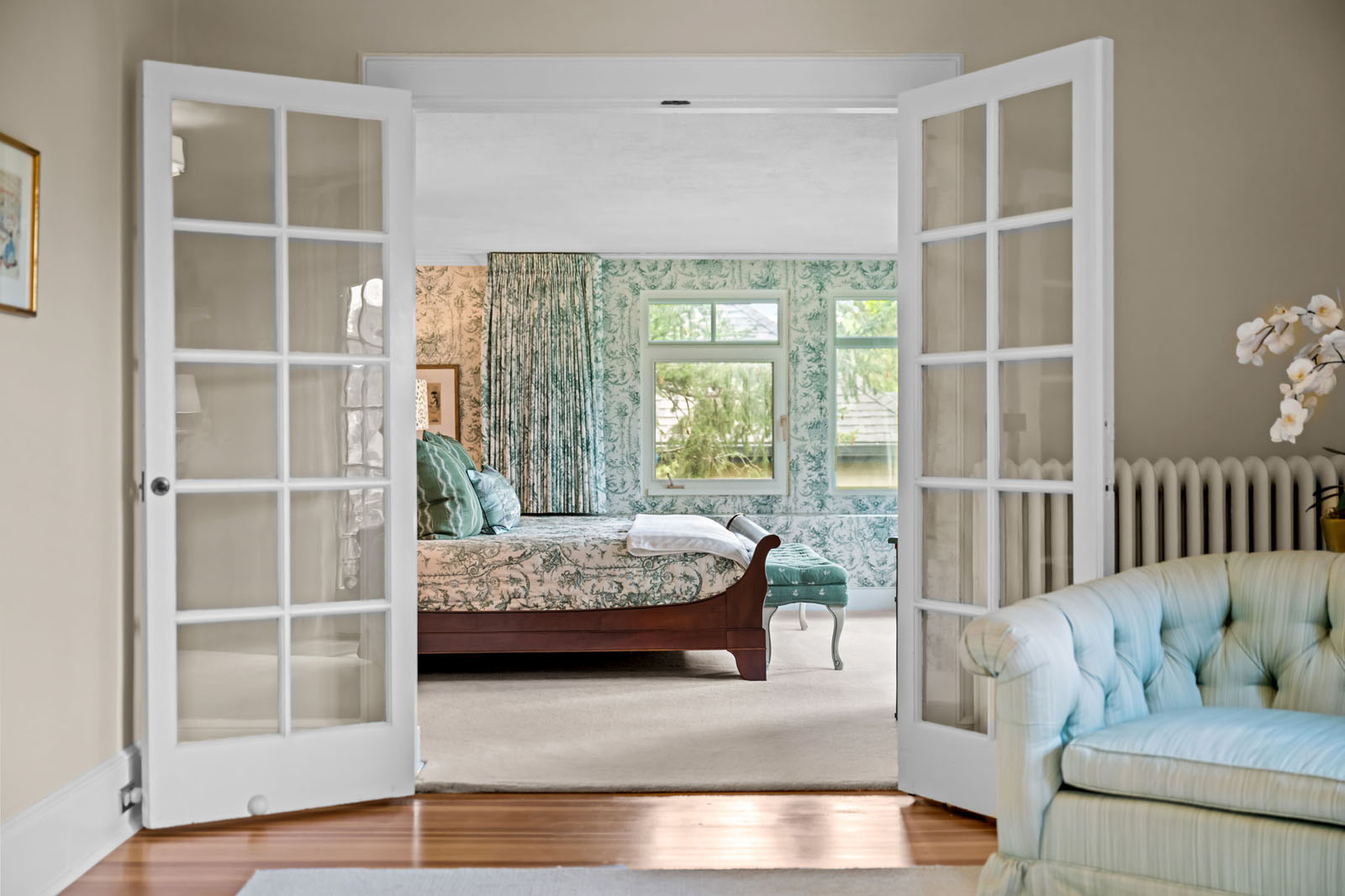 French doors open to a bedroom with green wallpaper