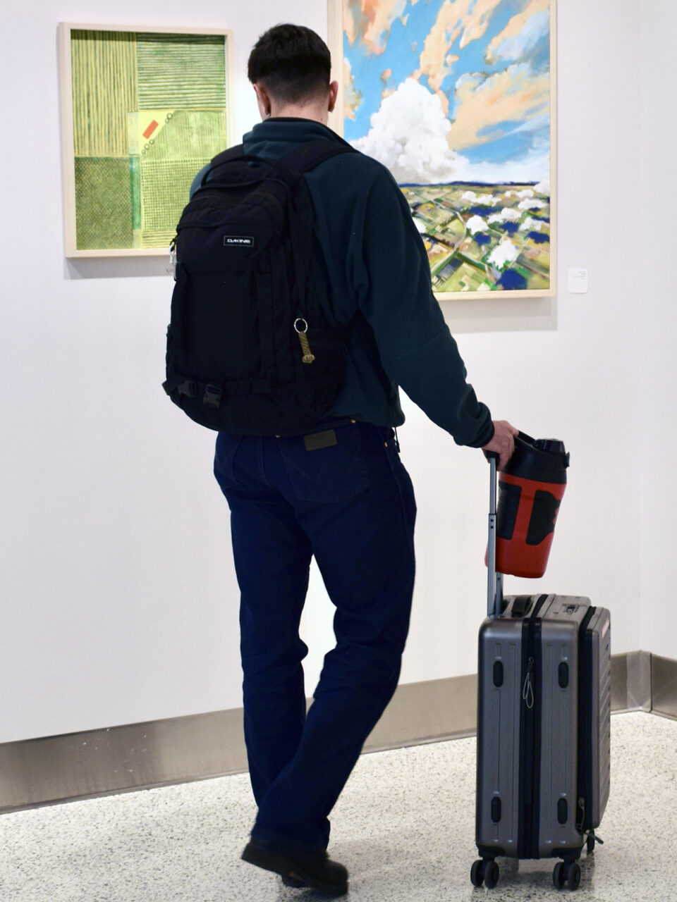 A man with a roller bag looks at art inside the Colorado Springs Airport