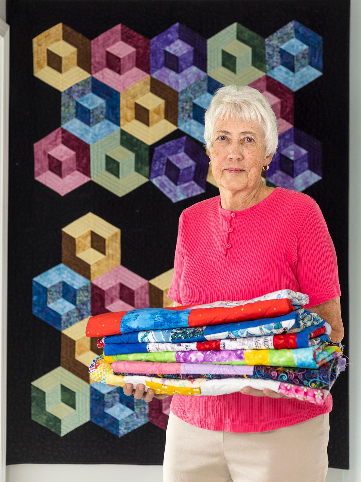 Elaine McFarlane holding a stack of folded quilts