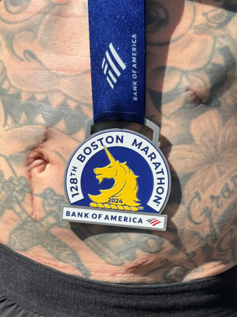 A Boston Marathon medal on a tattooed body