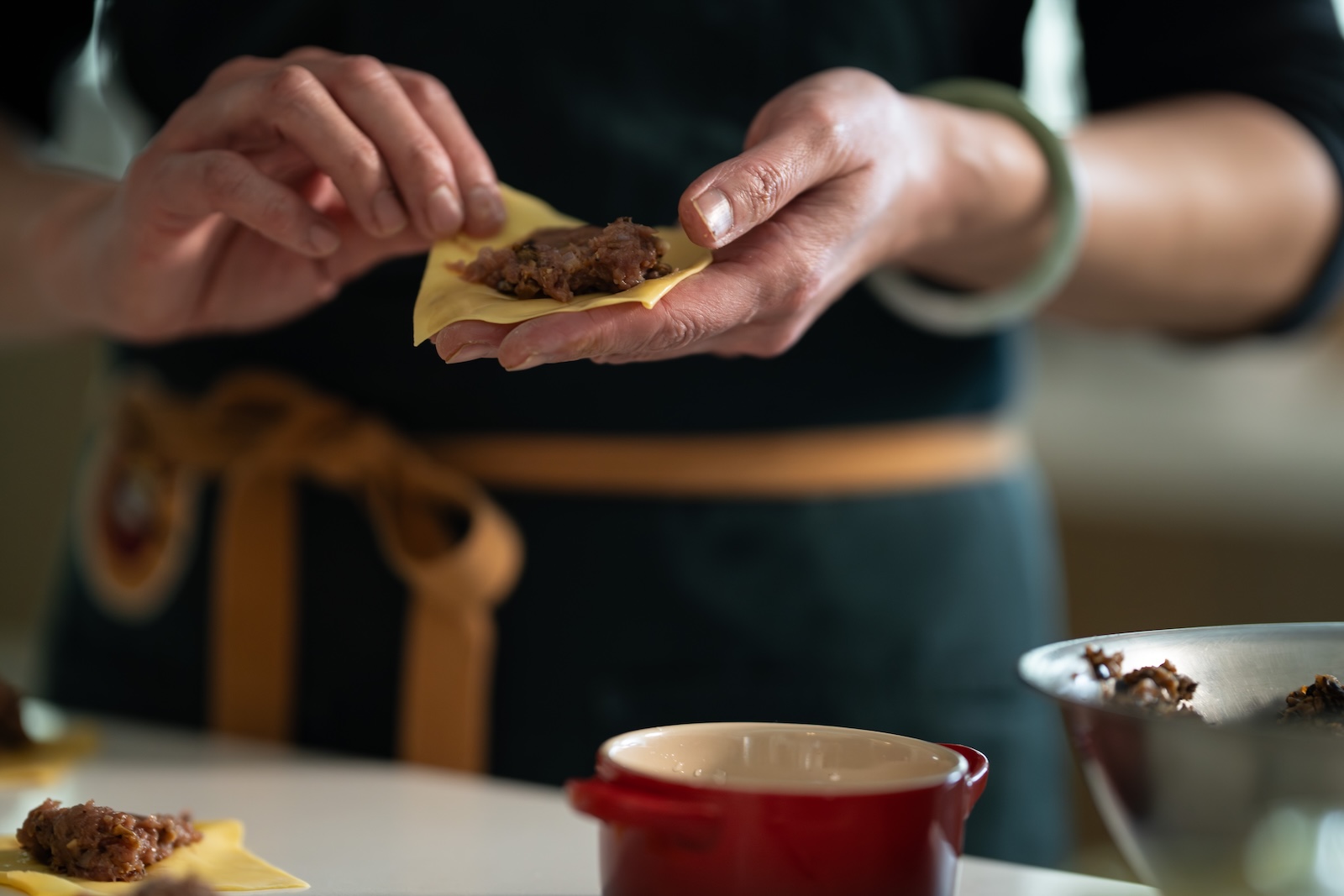 A pair of hands holds an open dumpling before being folded.