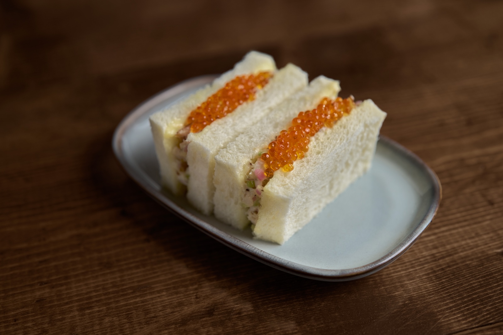 Two halves of a Japanese-style sandwich on white bread with trout roe
