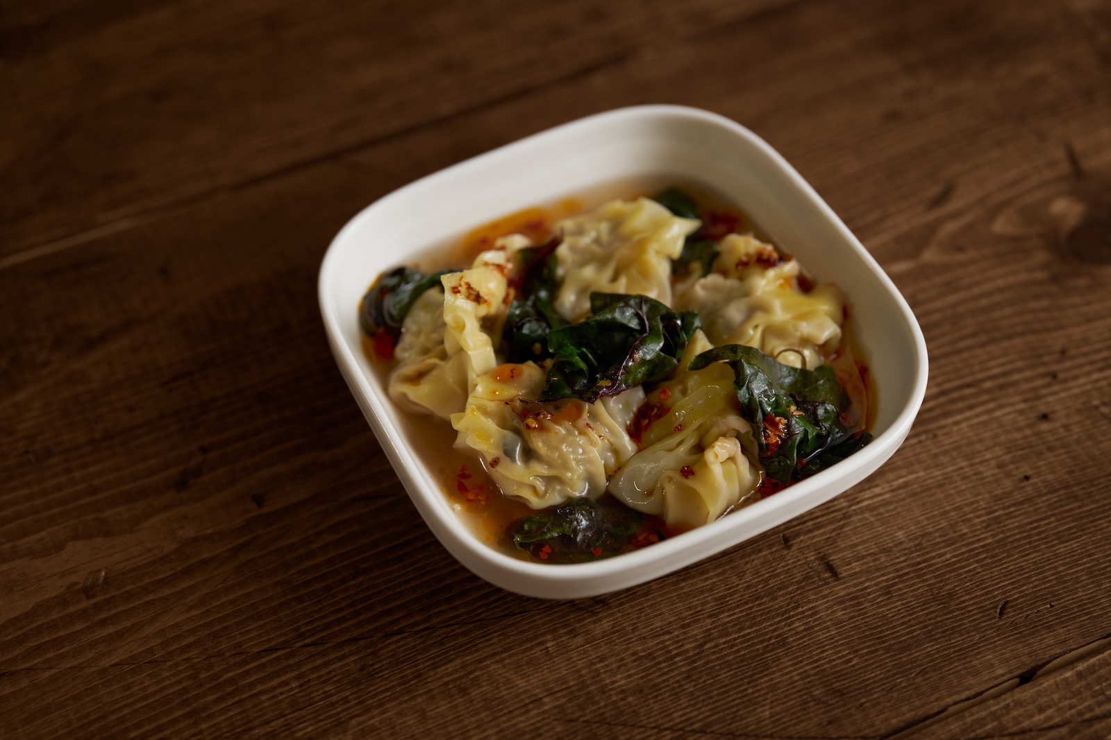 Wonton dumplings in chile oil in a white bowl