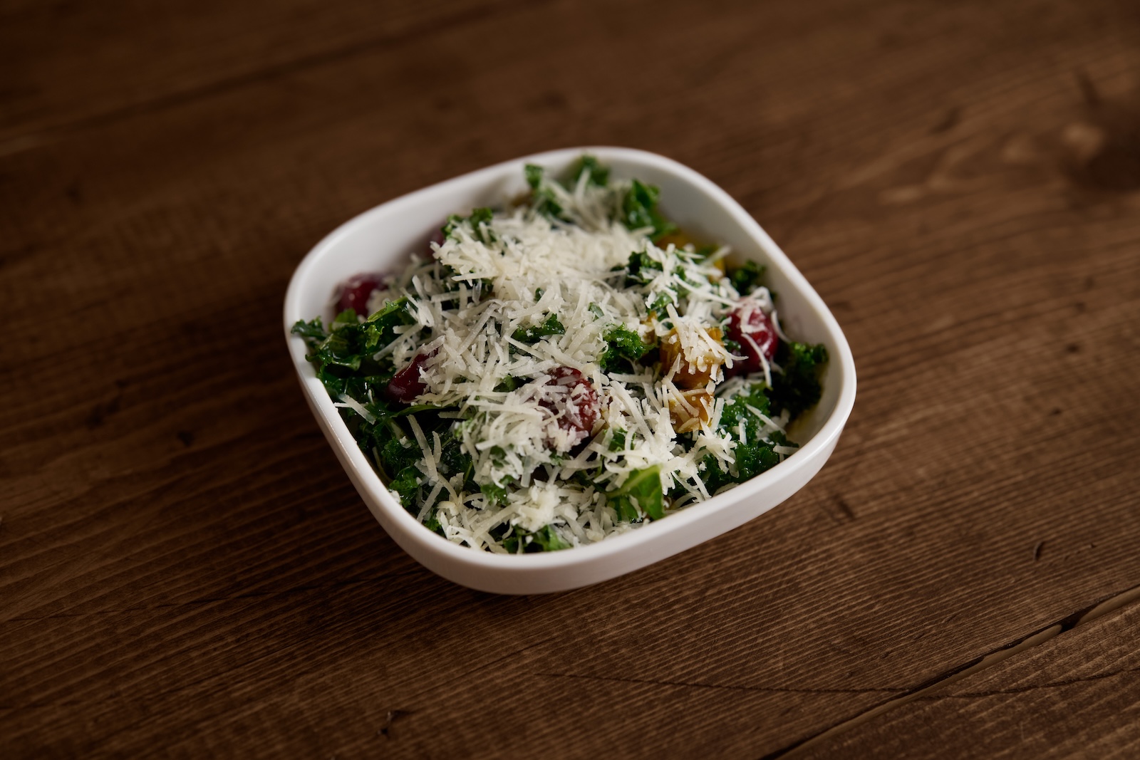 A kale salad with cherries and grated cheese on top