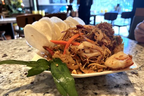 Vietnamese banana blossom salad with rice crackers and fresh herbs on a white plate