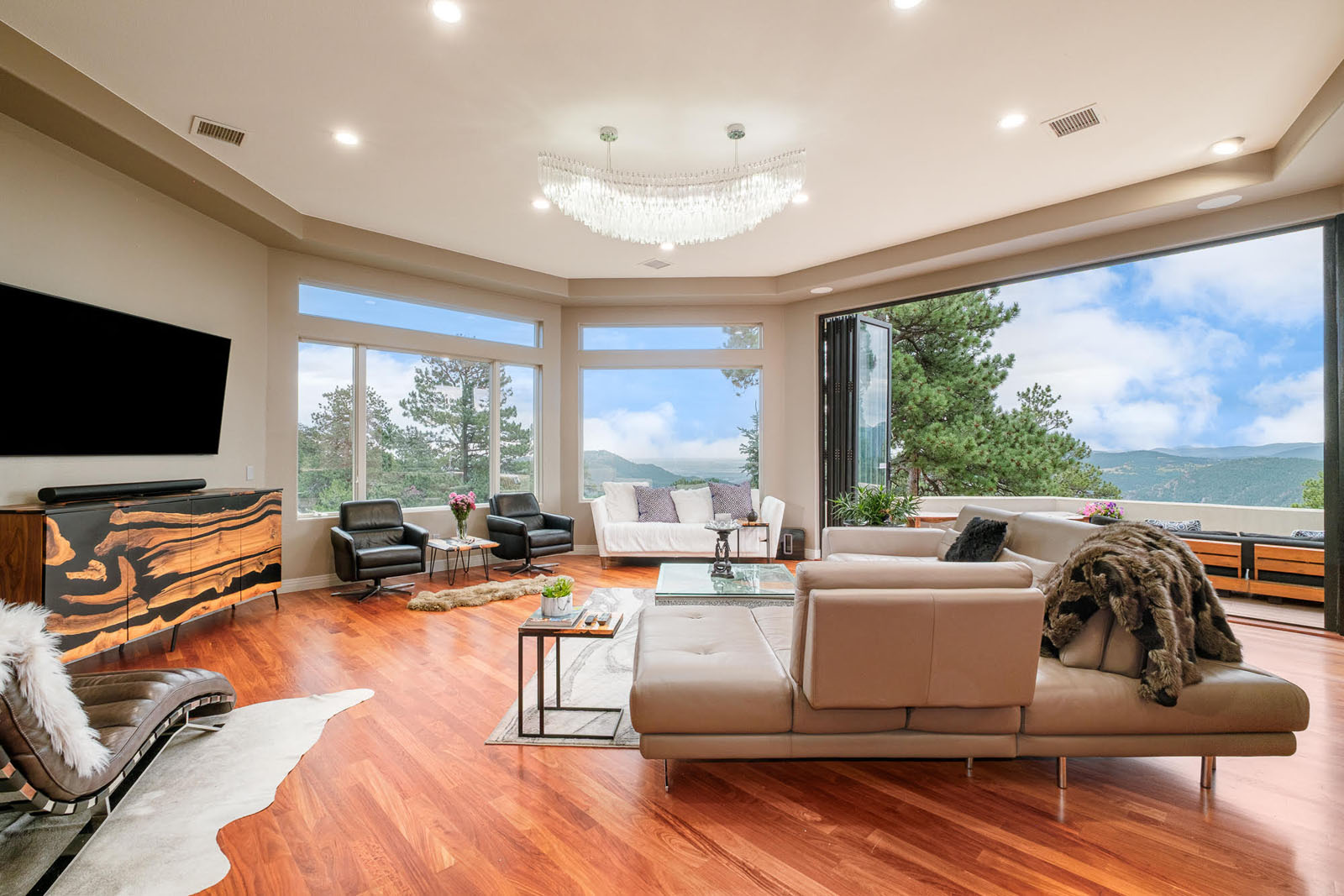 Living room with modern furniture, large picture windows, and cherry wood floors